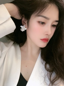 Close-up detail of silver pleated ruffle petal earrings on model with high gloss finish
