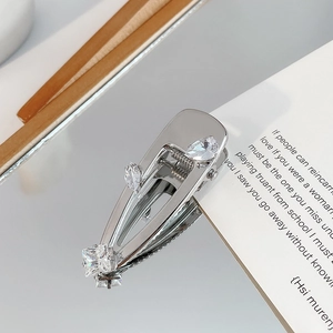 Macro detail of silver hair clip featuring sparkling square and teardrop zircon stones