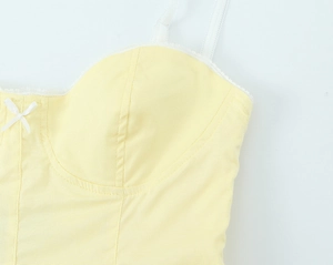 Dettaglio del camisole giallo pallido con bordo in pizzo bianco e fiocco decorativo
