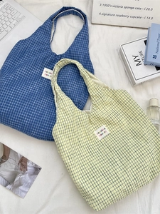 Retro blue and yellow checkered canvas tote bag on a cozy white fabric background
