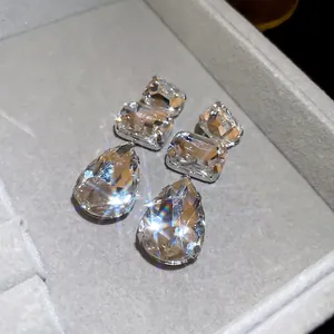 Elegant square and teardrop crystal fringe drop earrings in a grey jewelry box display
