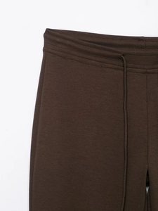 Detailed view of dark brown leisure pants with elastic drawstring waist and double stitching
