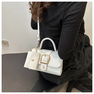 Close-up of a white square handbag featuring a golden buckle and a detachable small coin purse
