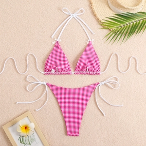 Detail of pink plaid bikini with halter ties and side-tie bottoms on sandy background