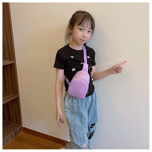 Detail view of purple child crossbody chest bag worn by a young model in a home setting