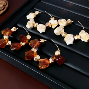 Chic geometric resin hoop earrings with amber brown and beige tones on black stands