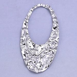 Macro detail of irregular oval silver pendant with hammered texture for DIY jewelry