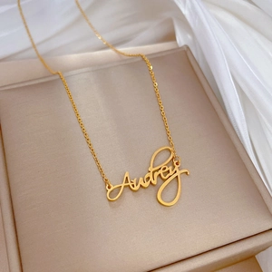 Minimalist gold titanium steel necklace with Audrey name pendant on silk background