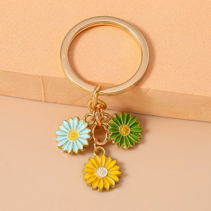 Detail of a golden keychain featuring blue, yellow, and green enamel daisy pendants