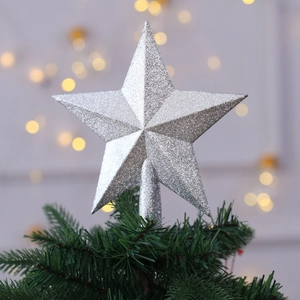 Sparkling silver glitter star topper mounted on a green Christmas tree with warm bokeh lights