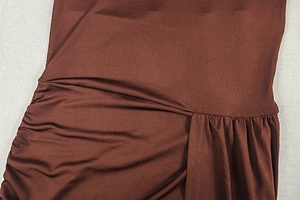 Gros plan détaillé du tissu froncé marron foncé et des coutures de la robe ajustée