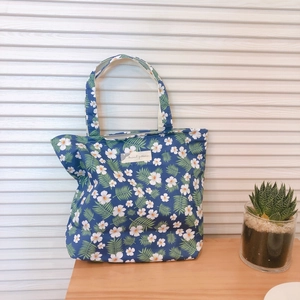 Detail of floral tote bag with white petals on navy blue fabric and silver zipper closure