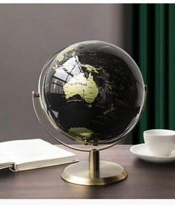 Détail d'un globe noir et doré avec support en métal brossé sur un bureau chic
