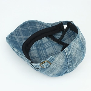 Detail of blue denim checkered beret featuring adjustable bronze metal buckle back