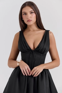 Detail of deep V-neck black satin mini dress with corset waist and bow tie ribbon