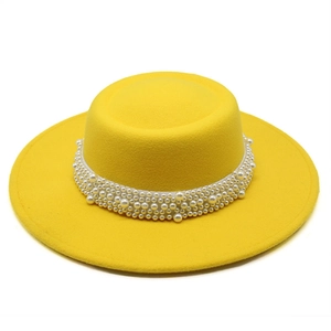Detail of a bright yellow wide-brim felt hat decorated with elegant white faux pearls