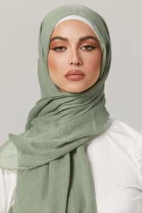 Close-up of sage green pleated cotton scarf with subtle fringe edges on female model