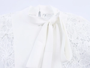 Detail of white blouse with elegant lace splicing and a delicate neck tie bow