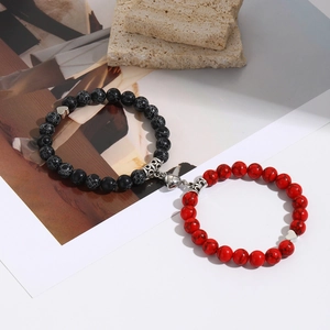 Detail of couple magnetic bracelets with black and red beads and heart clasp
