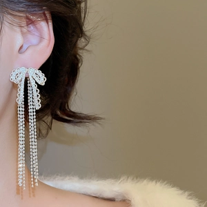 Detail of silver bow tassel earrings with sparkling zircon crystals on female model
