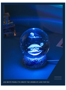 Detail of 3D crystal ball night light showing moon and shell laser engraving with blue glow