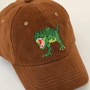 Detailed view of corduroy texture and green dinosaur embroidery on a brown baseball cap