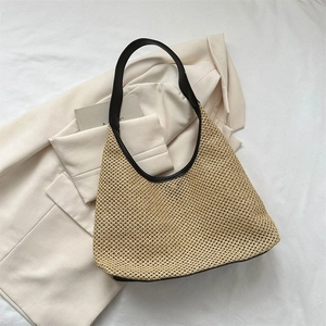 Handwoven straw tote bag with black leather handles in a natural beige hobo style