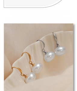 Detailed view of elegant white round pearls hanging from gold and silver metal hooks