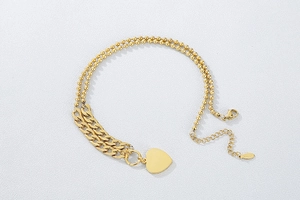 Detail of gold double-layered necklace featuring a heart pendant and Cuban chain links