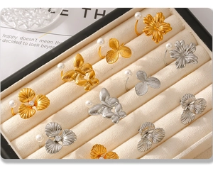 Detailed view of floral and butterfly rings with pearls on beige velvet jewelry tray