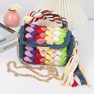 Detail of a handmade rainbow crochet crossbody bag with a gold twist lock and chain strap