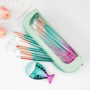Detail of mermaid scale brushes and mint green cosmetic bag with clear window