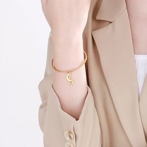 Detailed view of a gold celestial bangle with moon and star charms on a female model