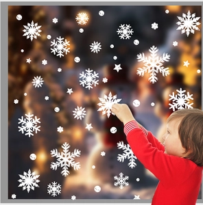 White snowflake window stickers being applied to glass for festive Christmas decoration