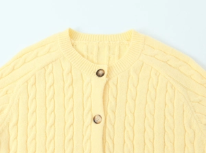 Detailed close-up of light yellow cable knit cardigan with buttoned crew neckline