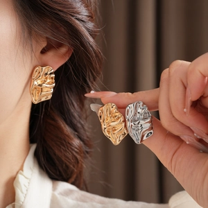 Detailed view of gold and silver irregular crinkle earrings with molten metal texture