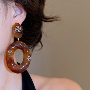 Detail showing retro dark brown resin hoop earrings with silver metal cross accents