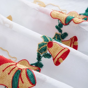 Macro shot of Christmas bell embroidery on white semi-transparent cafe curtain fabric