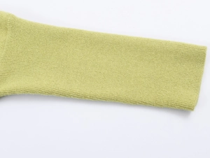 Close-up of grass green knit sweater sleeve showing fine fabric texture and neat stitching