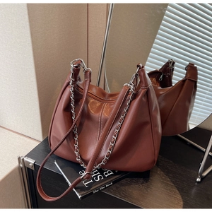 Detail of brown PU leather shoulder bag with metal chain strap and rear mirror reflection
