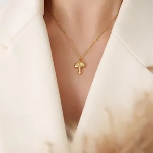 Detail of 18k gold mushroom pendant necklace with polished finish worn on model