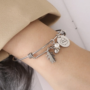 Vue détaillée du bracelet en acier avec perle, silhouette de fille et breloques de Noël