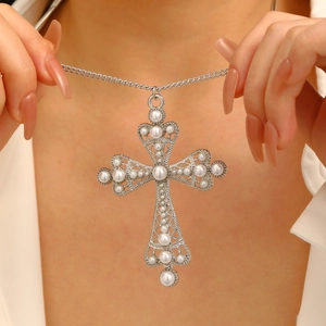 Detailed view of silver cross pendant featuring embedded pearls and sparkling rhinestones