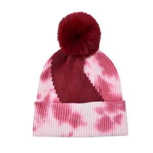 Detailed knit texture of red tie-dye beanie with large pompom and rolled cuff edge