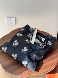 Detailed view of black textured jacquard fabric and vintage rose pattern on tote bag