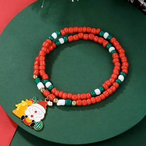 Detail of Christmas beaded bracelet with Santa charm on festive red and green background