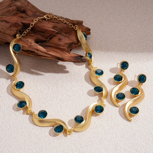 Vintage gold wavy necklace and earrings set with blue crystal accents on rustic wood