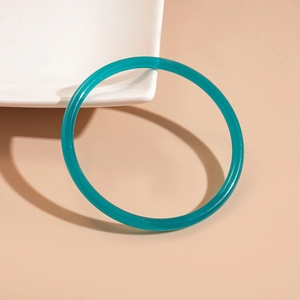 Detailed view of a slim turquoise acrylic bangle resting on a white ceramic plate