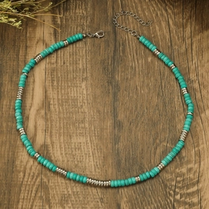 Detail of bohemian turquoise beads and silver spacers necklace on rustic wood surface