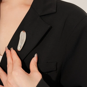 Polished silver liquid metal brooch shown on a black suit lapel for a modern style